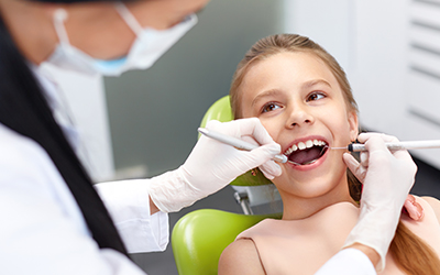 A dentist cleaning a young girls teeth