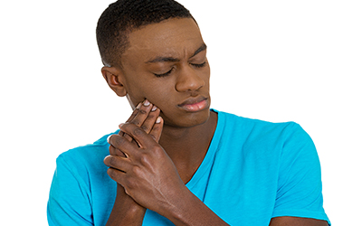 Sad young man holding his jaw in pain