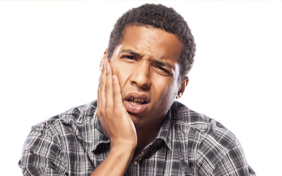 An older man older the side of his mouth in pain