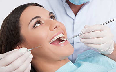 A close up of a woman getting her teeth checked out by the dentist